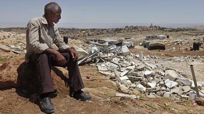 Suleiman Qaed, 54, sits in front of his demolished home in the Palestinian Bedouin community Jabal Al Baba, with the Israeli settlement of Maaleh Adumim in the background. Majdi Mohammed / AP Photo / May 1, 2014