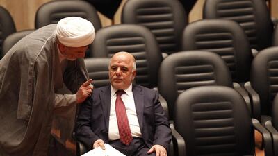 Shiite Sheikh Humam Hamoudi, left, Iraq's new deputy speaker of the Iraqi Council of Representatives, speaks with Iraq's new prime minister Haider Al Abadi as they attend a parliamentary session to vote on the country's new government at the parliament headquarters in Baghdad on Monday. Thaier Al Sudani / Reuters