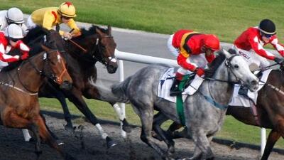 Jockey Oscar Chavez rides Captain Obvious (gray) through the field to win the fourth race of the Fourth Carnival Race Meeting at Meydan Racecourse on January 20, 2012.
