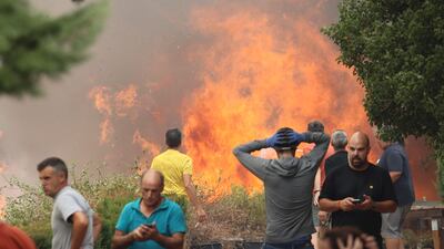 People stand near the forest fire in Anon de Moncayo, Spain. The fire has already forced the evacuation of eight villages and 1,500 people in Zaragoza province. AP