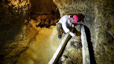 An archaeologist brushes a newly-discovered mummy laid inside a sarcophagus, part of a collection found in burial chambers dating to the Ptolemaic era (305-30 BC) at the necropolis of Tuna el-Gebel in Egypt's southern Minya province. AFP