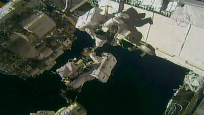 Astronauts Ricky Arnold, centre, attached to robotic arm, and Drew Feustel, above, work during a spacewalk outside the International Space Station. NASA via AP