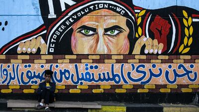 An Iraqi youth leans on a wall with a graffiti mural at the anti-government sit-in Baghdad's Tahrir Square. AFP