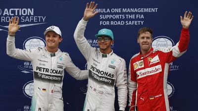 Mercedes driver Lewis Hamilton, center, of Britain waves with teammate Nico Rosberg, left, of Germany and Ferrari driver Sebastian Vettel of Germany after qualifying for the Malaysian Formula One Grand Prix at Sepang International Circuit in Sepang, Malaysia, Saturday, March 28, 2015. Hamilton took pole position for Sunday's race ahead of Vettel. Rosberg finished third. (AP Photo/Vincent Thian)