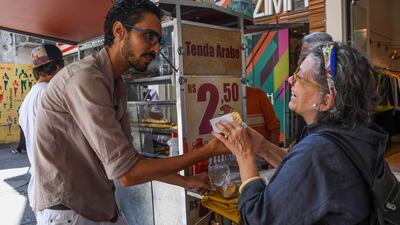 Egyptian immigrant Mohamed Ali Kenawy, who was attacked by four men screaming "Go back to your country!", attends to a customer at his food stand in the Copacabana neighborhood in Rio de Janeiro on August 24, 2017. Apu gomes / AFP
