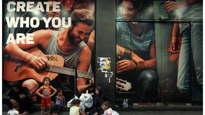 Sanaa, second right, having iftar with her children, while sitting next to relatives near a clothes shop advert in Beirut, Lebanon on June 10, 2016. Sanaa, 23, mother of three children, begs on Hamra street in Beirut. The family fled Syria two years ago, after her husband went missing. Her iftar meal is lentil soup with chicken and rice, which she received from passers-by. “Ramadan is about kindness and giving. I mostly like the decorations,” she says. Photo by Alia Haju