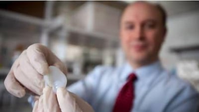 Larry Bonassar, Cornell Associate Professor of Mechanical Engineering, holds a fabricated ear printed with a 3D printer.