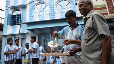 Shib Shankar Patra, second from right, serves tea to fans and customers in front of his apartment painted in blue-and-white. AFP