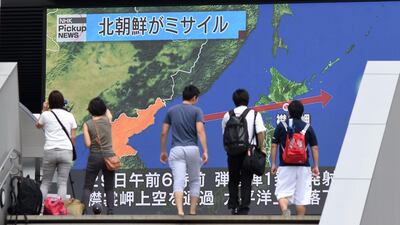 Pedestrians walk in front of a huge screen displaying a map of Japan and the Korean Peninsula following a North Korean missile test that passed over Japan. Toshifumi Kitamura / AFP