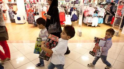 Twins Faris and Fahad, 5, and their little brother Ahmad Kanakrie, 3, carry their new toys while their family enjoys an evening out shopping in Abu Dhabi. Silvia Razgova / The National