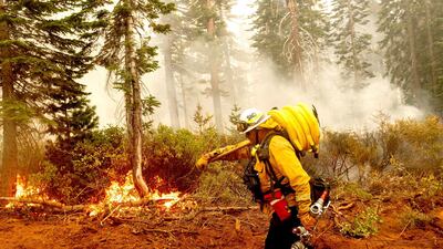 Cal Fire Battalion Chief Craig Newell carries hose while battling the North Complex Fire in Plumas National Forest, California, US on 14 September 14 2020. Noah Berger / AP