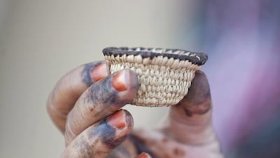 Woman displays a mini basket she has woven. Silvia Razgova / The National