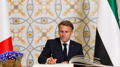 French President Emmanuel Macron signs the guestbook at Qasr Al Watan during an official visit reception in Abu Dhabi. Ryan Carter / UAE Presidential Court