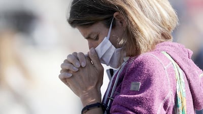 A woman wearing a face mask to curb the spread of Covid-19 holds her hands as she prays during Pope Francis' Angelus noon prayer in St Peter's Square at the Vatican. AP Photo