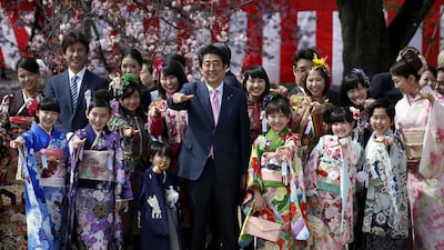 Japan's Prime Minister Shinzo Abe poses with child actors, members of Japanese idol group Momoiro Clover Z at a cherry blossom viewing party at Shinjuku Gyoen park in Tokyo, Japan. REUTERS