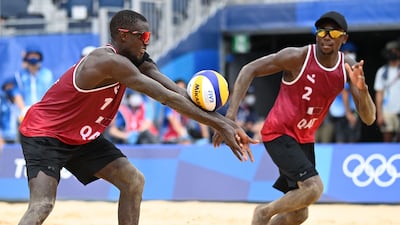 Qatar's Ahmed Tijan (R) watches as partner Cherif Younousse digs the ball on their way to winning the men's beach volleyball bronze medal match against Latvia at Shiokaze Park in Tokyo.