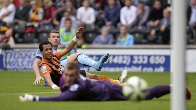Manchester City's Edin Dzeko, back, watches as he scores his team's third goal past Hull City's Liam Rosenior, centre, and keeper Allan McGregor, near, during City's 4-2 win over Hull at the KC Stadium on Saturday. Philip Brown / Reuters