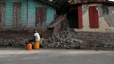 Children sit in front of houses that were damaged in Gros Morne. Reuters