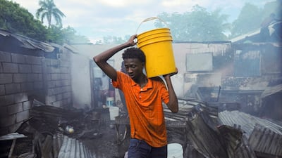 A volunteer helps firefighters battle a blaze at a shelter in Port-au-Prince, Haiti. Reuters