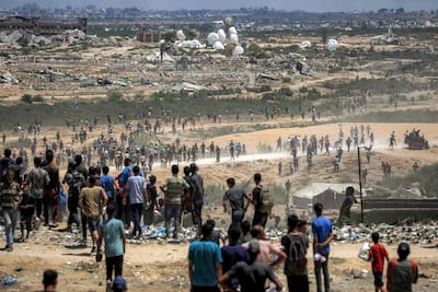 Palestinians rush to the scene as pallets of aid are dropped into Gaza. AFP