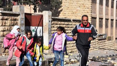 A Syrian man leads students out of a school in the Furqan area of western Aleppo where at least eight children were killed by rebel rocket fire on November 20, 2016. George Ourfalian / AFP