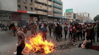 Anti-government protesters set a fire while security forces use tear gas during clashes in central Baghdad. AP Photo
