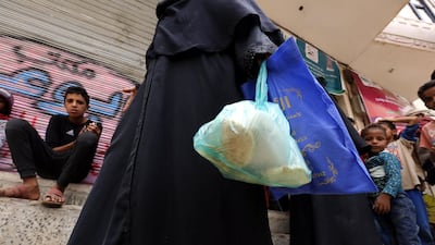 A displaced Yemeni, who fled her home in the war-torn city of Hodeidah, receives food rations provided by a charity in Sanaa. Yahya Arhab / EPA