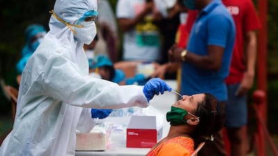 A healthcare worker in protective gear takes a nasal swab from a Mumbai resident for a Covid-19 test. India's health ministry declared 92,071 new cases of the pandemic on Monday, bringing the total so far to more than 4.85 million. AFP
