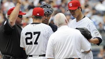 Wang Chien-Ming, right, rests his glove on the shoulder of the trainer Steve Donahue as umpire Wally Bell signals the bullpen for a new pitcher.