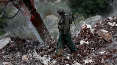 An Israeli soldier walks next to a digger. AP Photo