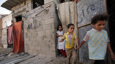 Heba Alwadiya, 11, stands at a cloth-covered door as her sister and brother leave their family house in Gaza City. Most of their family's clothes and food comes from donations. Adel Hana / AP