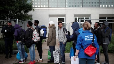 Migrants with their belongings line up as they pass French police who evacuated hundreds of migrants living in makeshift camps in Paris, France. Benoit Tessier / Reuters