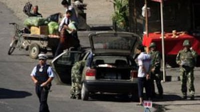 Armed Chinese policemen and soldiers check an ethnic Uighur's car at a checkpoint on the outskirts of the city of Urumqi in Xinjiang.