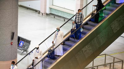 Travellers from the first group of arrivals for the Hajj observe social distancing as they descend an escalator at Jeddah's King Abdulaziz International Airport on July 25, 2020. Saudi Ministry of Hajj and Umra / AFP