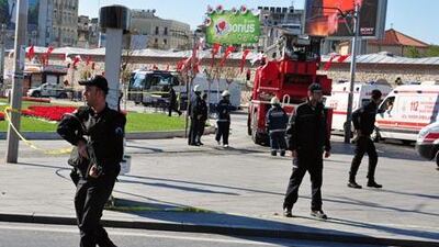 Police officers surround the scene while firefighters and ambulances wait nearby after an explosion in Taksim square.
