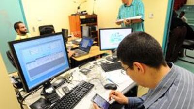 Workers at a Qatar Statistics Authority station transfer data from PDAs to a database server.