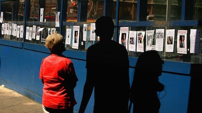 People look at a long line of missing people posters placed by friends and relatives after the bombings, outside King's Cross station