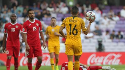 Australia's defender Aziz Behich holds the ball as Yousef Al Rawashdeh lies on the ground. AFP