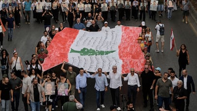 Relatives of victims hold portraits of their loved ones and carry the Lebanese flag. AP