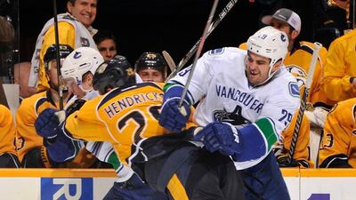 Matt Hendricks, centre, of the Nashville Predators collides with Tom Sestito, right, of the Vancouver Canucks at Bridgestone Arena on December 3, 2013, in Nashville, Tennessee. Frederick Breedon / Getty Images