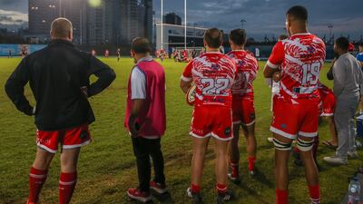 Dubai Tigers players and staff watch the game from the sidelines.