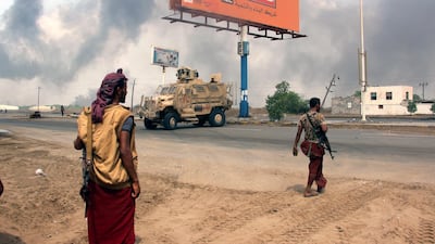 Yemeni government forces patrol a road as smoke billows from a Houthi position in the port of Hodeidah. EPA