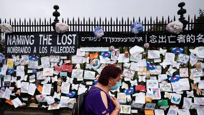 A woman passes a fence outside Brooklyn's Green-Wood Cemetery adorned with tributes to victims of COVID-19 in New York on on May 28, 2020. AP Photo
