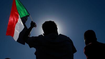 A Sudanese protester lifts a national flag during a demonstration calling for a return to civilian rule in the capital Khartoum, on November 21, 2021. AFP
