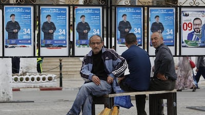 Men sit on a bench by electoral posters near Algiers, Monday, May 1, 2017. AP Photo / Sidali Djarboub