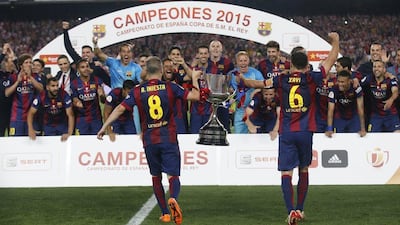 Barcelona's Andres Iniesta, left, and Xavi take the Copa del Rey trophy to their teammates as they celebrate after winning on Saturday night. Reuters / Albert Gea