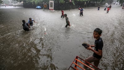 Children wade through a flooded street in Mumbai, India, July 5, 2022. EPA