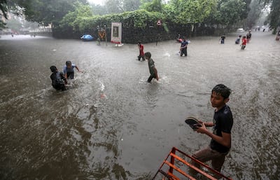 Children wade through a flooded street during heavy rain in Mumbai on Tuesday. Photo: EPA
