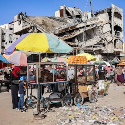A vendor sells pastries and baked goods from his stall before a collapsed building along a market street in Gaza city. AFP