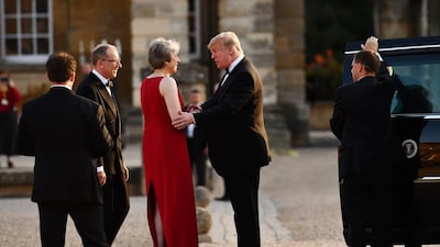 Ms May, centre left, shakes hands with Mr Trump, as her husband Philip, second left, looks. AP